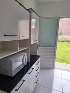 uma cozinha com armários brancos e um micro-ondas em Residencial Caramujo em Florianópolis