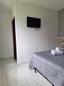 um quarto com uma cama e uma televisão de ecrã plano na parede em Residencial Caramujo em Florianópolis
