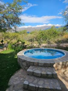 uma banheira de hidromassagem num círculo de pedra num quintal em Raíces serranas em Villa de Las Rosas