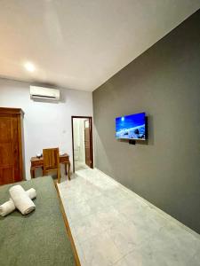 a bedroom with a flat screen tv on the wall at Chua Guest house Canggu in Canggu