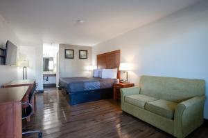 a hotel room with a bed and a couch and a chair at Hotel Serene in Glendale