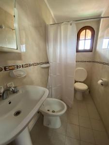 a white bathroom with a toilet and a sink at Hotel Portofino by CPH in Villa Gesell