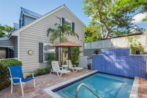 a house with a swimming pool with chairs and an umbrella at Old Town Garden Villas - Andros Suite in Key West
