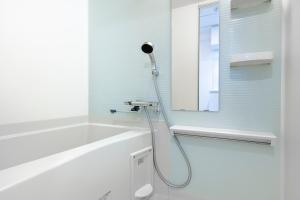 La salle de bains blanche est pourvue d'une douche et d'un miroir. dans l'établissement Brilliant MK- III, à Tokyo