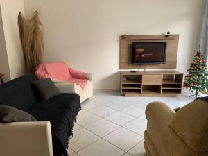 uma sala de estar com televisão e uma árvore de Natal em Apartamento no Guarujá para 8 pessoas no Guarujá