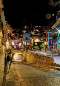 a city street at night with a stone wall at Hotel Casa Posos in Guanajuato