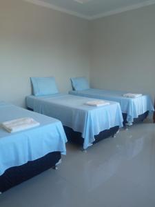 three beds in a room with blue covers on them at House Suites in Paragominas