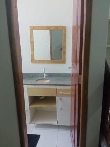 a bathroom with a sink and a mirror at House Suites in Paragominas