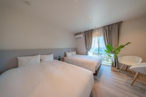 Habitación de hotel con 2 camas y mesa en Crystal Villa ikema, en Isla Miyako