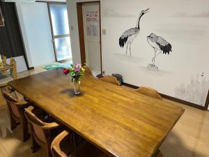 una mesa de madera con un jarrón de flores. en ゲストハウス　アロマ, en Ureshino