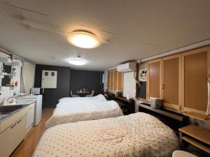 2 camas en una habitación pequeña con cocina en ゲストハウス　アロマ, en Ureshino
