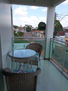 a balcony with a table and chairs and a view at House Suites in Paragominas