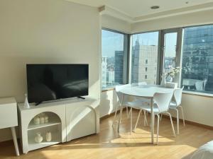 een woonkamer met een televisie en een tafel en stoelen bij Hongik univ station Exit 1 in Seoul