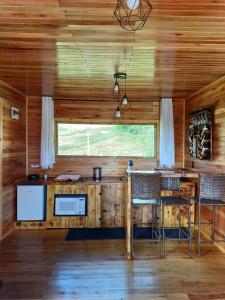 a kitchen with a bar in a cabin with wooden walls at Recanto do Ipê cabana 01 in Urubici