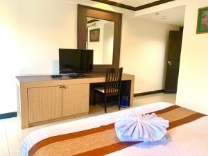 a room with a bed with a television and a desk at Tanawit HuaHin Hotel in Hua Hin