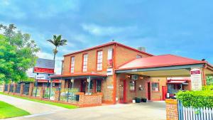 a red brick building with a palm tree behind it at Early Australian Motor Inn in Mildura