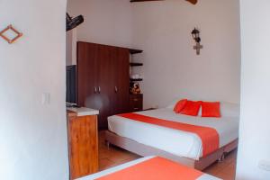 um quarto com uma cama com almofadas vermelhas em El Retiro Barichara 206 em Barichara