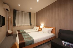 Giommachiにある谷町君 HOTEL 京都駅東29のベッド2台とソファが備わるホテルルームです。