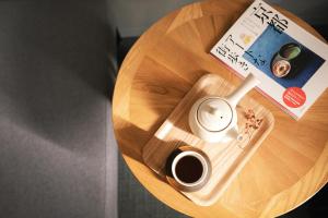 a wooden table with a cup of coffee and a book at 谷町君 HOTEL 京都駅東29 in Giommachi