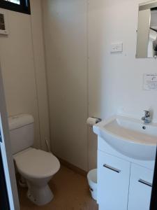 La salle de bains est pourvue de toilettes blanches et d'un lavabo. dans l'établissement Mt Isa Caravan Park, à Mount Isa