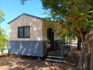 a tiny house sitting next to a tree at Mt Isa Caravan Park in Mount Isa