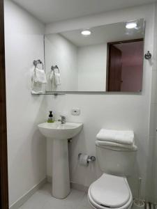 ein Badezimmer mit einem WC, einem Waschbecken und einem Spiegel in der Unterkunft Hermoso apartamento en Cajicá in Cajicá