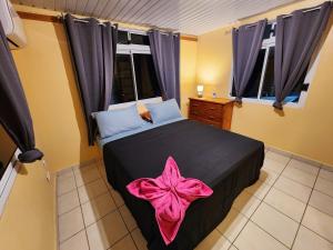 a bedroom with a black bed with a pink bow on it at Fare Moana Bord de Mer Fare Tepua Lodge in Uturoa