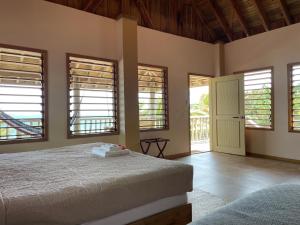 ein Schlafzimmer mit einem Bett in einem Zimmer mit Fenstern in der Unterkunft Hotel Guanaja in Guanaja