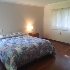 Un dormitorio con una cama y una lámpara y una ventana. en Casa con pileta en Pinares de Santa Clara, en Santa Clara del Mar