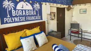 sypialnia z łóżkiem z żółtymi i niebieskimi poduszkami w obiekcie ONLY YOU MOTU w mieście Bora Bora