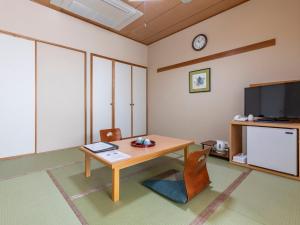 a living room with a table and a tv at Tennenonsen Harunonoyu in Kochi