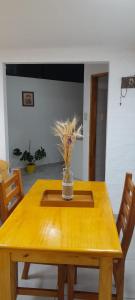een houten tafel met een vaas met bloemen erop bij Casa Belén in Toay