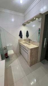 La salle de bains est pourvue d'un lavabo, de toilettes et d'un miroir. dans l'établissement Residencial Cordeiro, à Balneário Camboriú