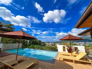 a swimming pool with two umbrellas and a view at Villa Tantawan Resort - Private Pool Villas in Kamala Beach