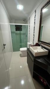 La salle de bains est pourvue d'un lavabo, de toilettes et d'un miroir. dans l'établissement Residencial Cordeiro, à Balneário Camboriú