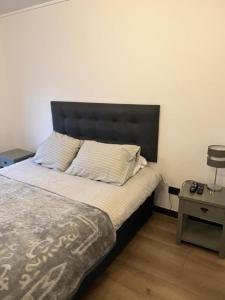 a bed with a black headboard in a bedroom at Las Condes, Apartamento para 4 con Piscina in Santiago