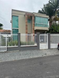 a white fence in front of a house at Casa com piscina em itapema in Itapema