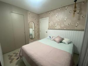 a small bedroom with a bed and a mirror at Casa com piscina em itapema in Itapema