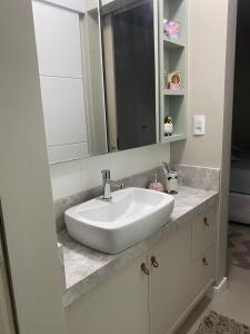 a bathroom with a white sink and a mirror at Casa com piscina em itapema in Itapema