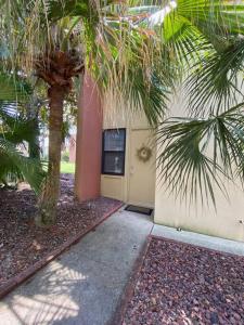 a building with a palm tree next to a sidewalk at Gulf Breeze Condo w Pool Access! in Gulf Breeze