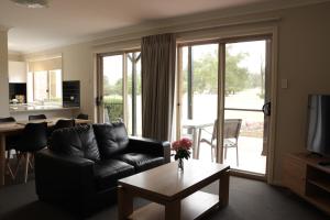 uma sala de estar com um sofá de couro preto e uma mesa em Cootamundra Heritage Motel & Apartments em Cootamundra