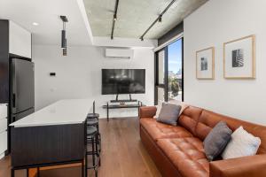 a living room with a brown leather couch and a flat screen tv at Boutique Stays - Camillea in Melbourne