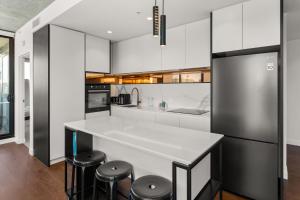 a kitchen with white cabinets and a counter with stools at Boutique Stays - Camillea in Melbourne