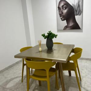 una mesa de comedor con sillas amarillas y un jarrón. en Apartamentos San José, en Cartagena de Indias