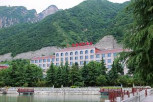 a building with people on top of it next to a mountain at Huashan Xinyuan International Hotel in Huayin