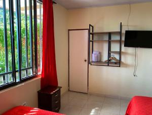 a bedroom with a door and a red curtain at Hotel Casa campestre HH in Quimbaya