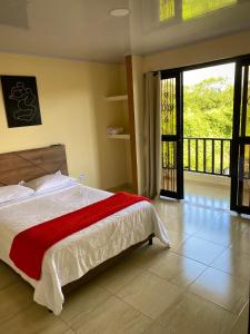 a bedroom with a bed with a red blanket at Hotel Casa campestre HH in Quimbaya