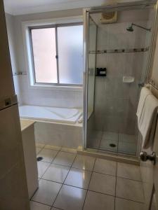 ein Bad mit einer Dusche, einer Badewanne und einem Fenster in der Unterkunft Cootamundra Heritage Motel & Apartments in Cootamundra