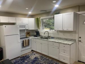 a kitchen with white cabinets and a sink and a window at Bellaire Midtown Cottage in Bellaire