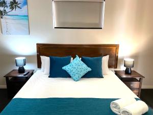 a bedroom with a bed with blue and white pillows at Cityville Apartments & Motel in Rockhampton